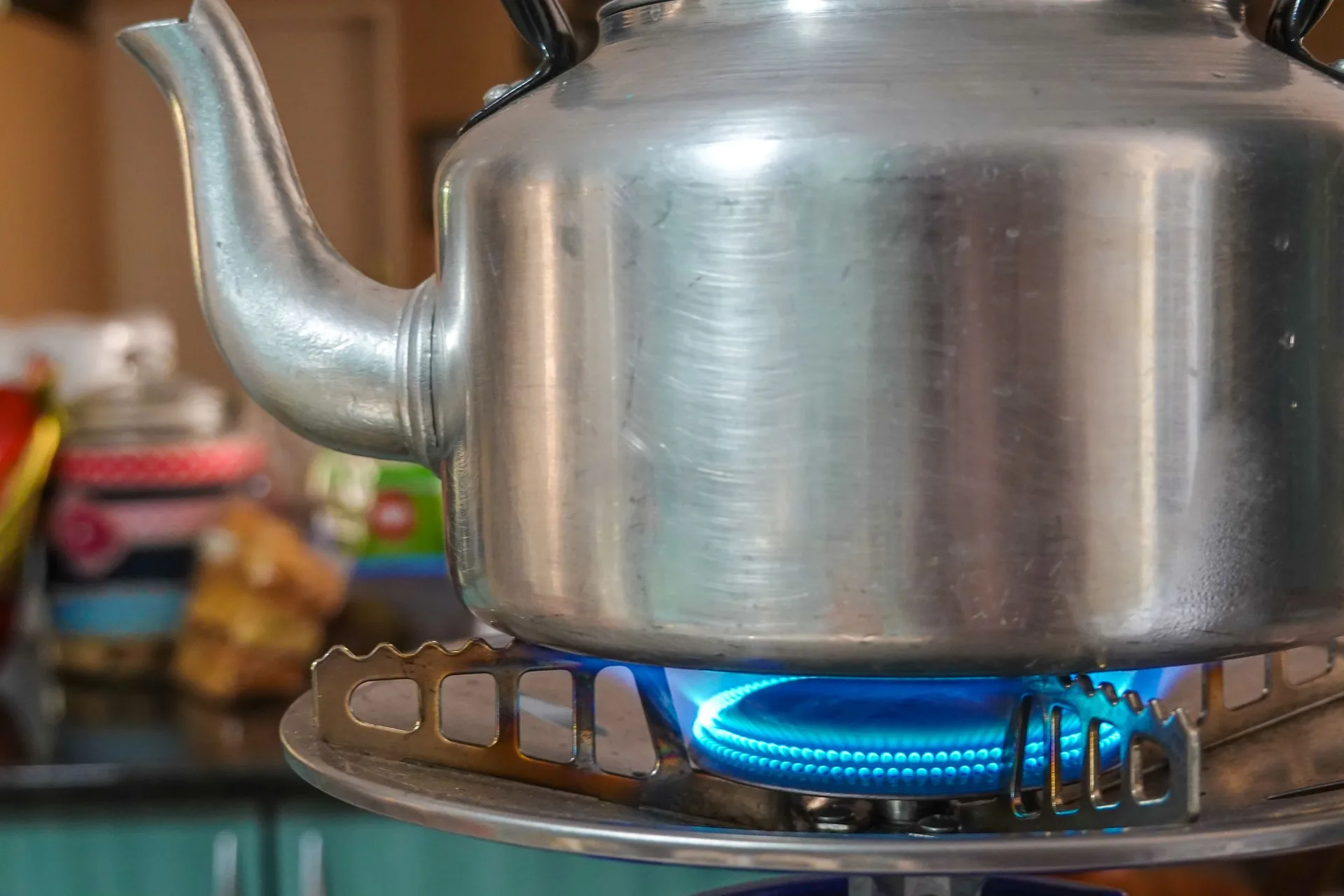 Blue flame warming a kettle on a residential gas stove