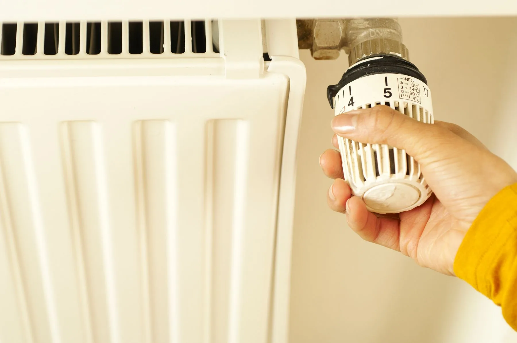 Hand adjusting a home heating thermostat